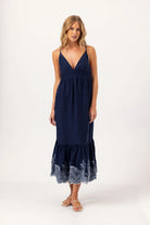 Woman wearing a navy blue dress with lace hem on a white background