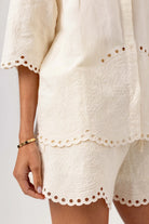 White lace dress with scalloped hem on a plain background