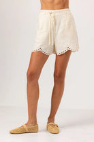 Beige shorts with lace trim worn by a person on a white background