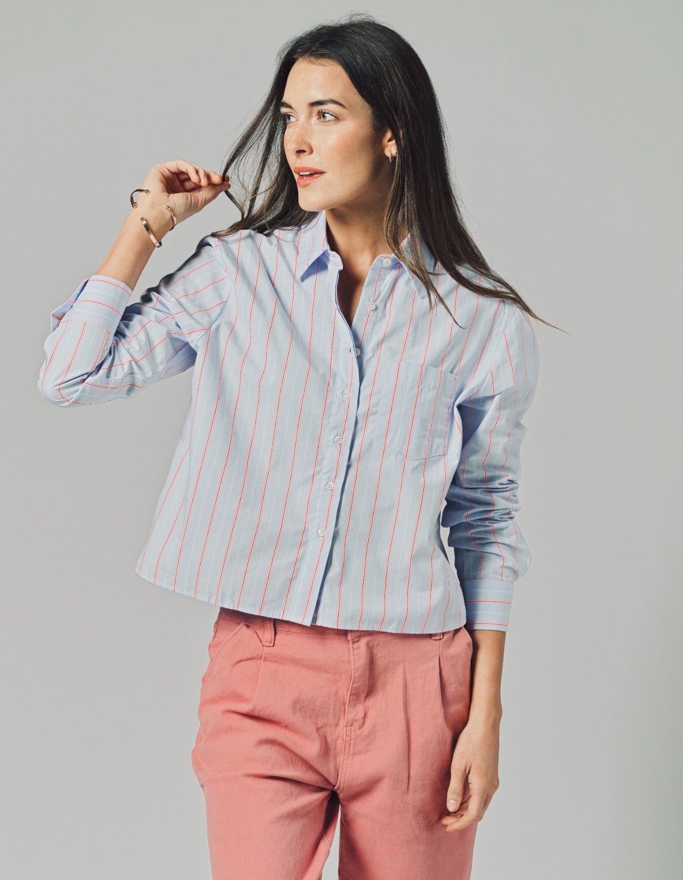 woman wearing a blue and red striped blouse with red pants and a blue background