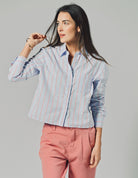 woman wearing a blue and red striped blouse with red pants and a blue background