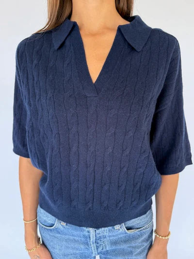 Navy blue cable knit sweater worn by a person on a light gray background