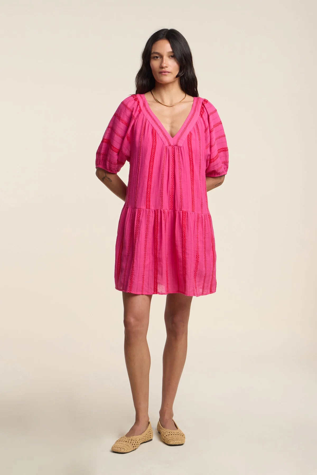 Woman wearing a pink dress on a plain background