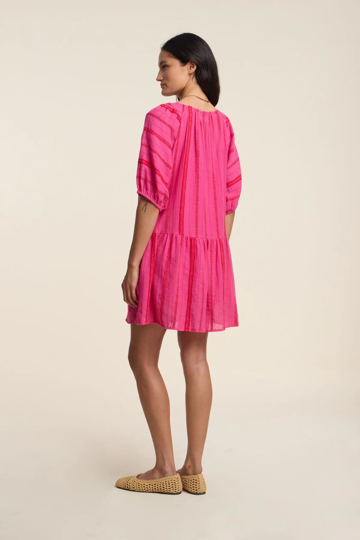 Woman wearing a bright pink dress on a beige background
