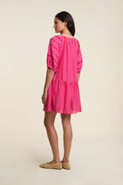Woman wearing a bright pink dress on a beige background