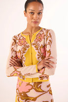 Woman wearing a floral patterned cardigan over a yellow shirt on a white background