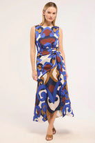 A sleeveless midi wrap dress with a blue, brown, and white abstract pattern, modeled against a plain light background.