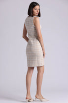 Woman wearing a sleeveless, patterned dress against a plain background