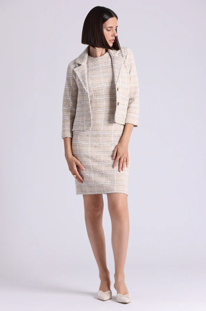 Woman wearing a beige and white checkered suit on a white background