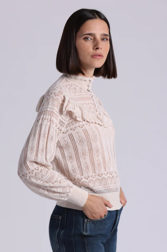 Woman wearing a beige lace blouse against a plain background