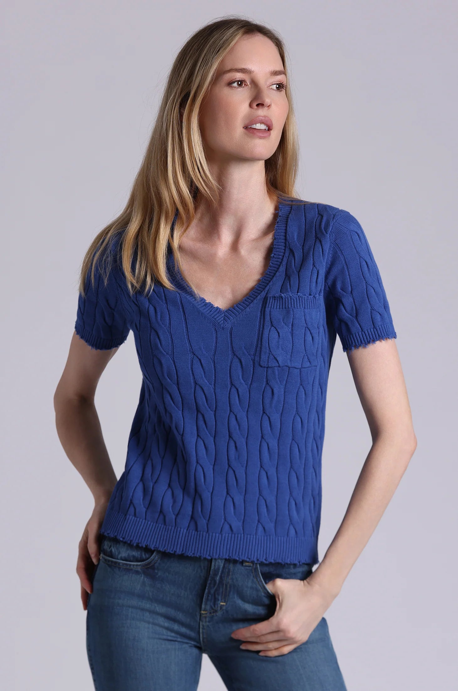 Woman wearing a blue knitted top with a plain background