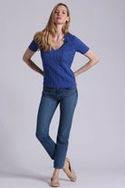 Woman wearing a blue top and jeans on a plain background