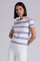 Woman wearing a white and blue striped shirt against a plain background