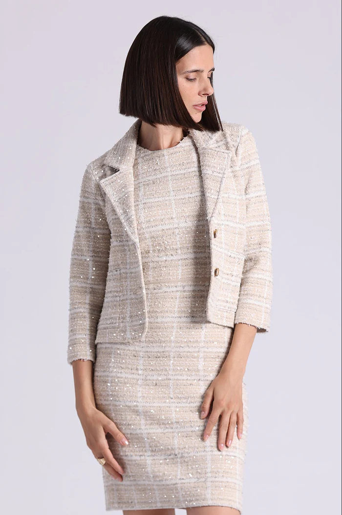 Woman wearing a beige tweed suit on a white background