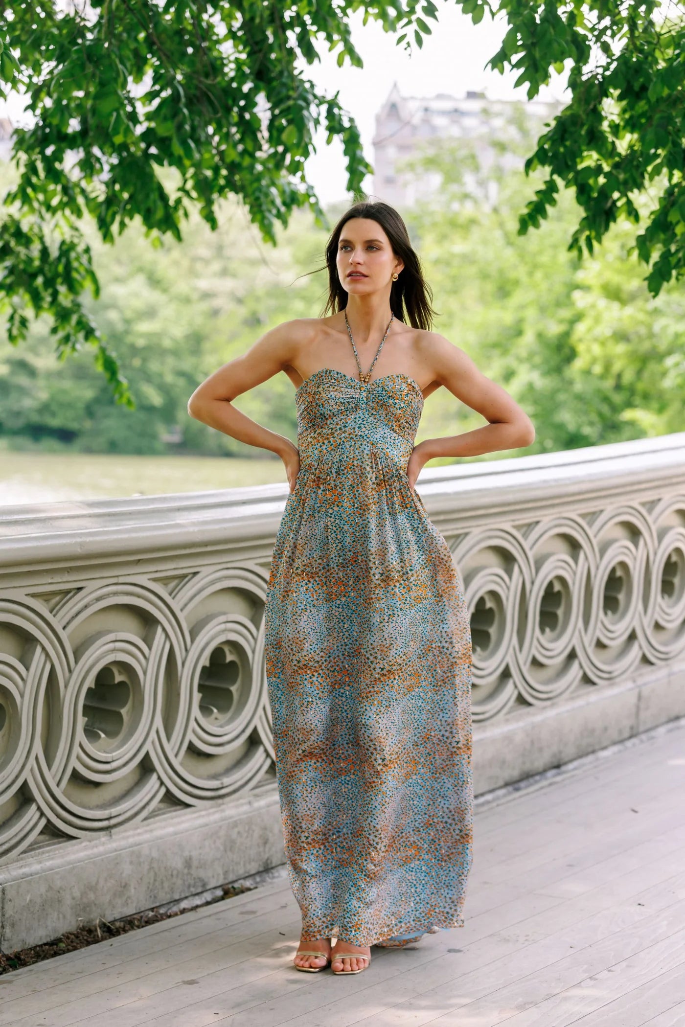 Woman in a strapless dress standing on a stone pathway with greenery in the background