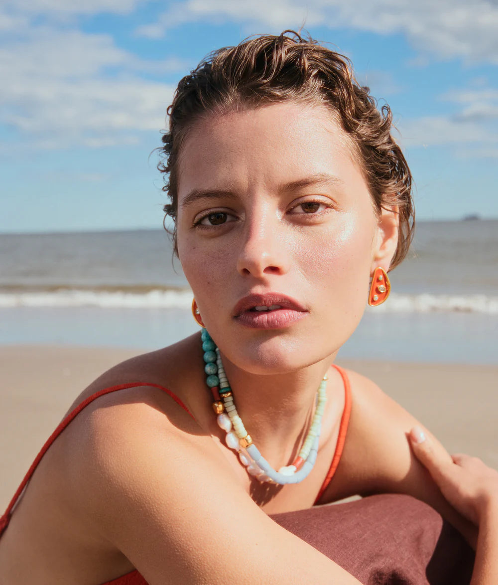 Woman sitting on a beach with ocean and sky in the background