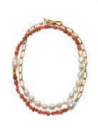 Necklace with coral and pearl beads on a gold chain against a white background