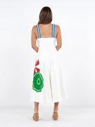 Woman wearing a white dress with a green and red design on a white background