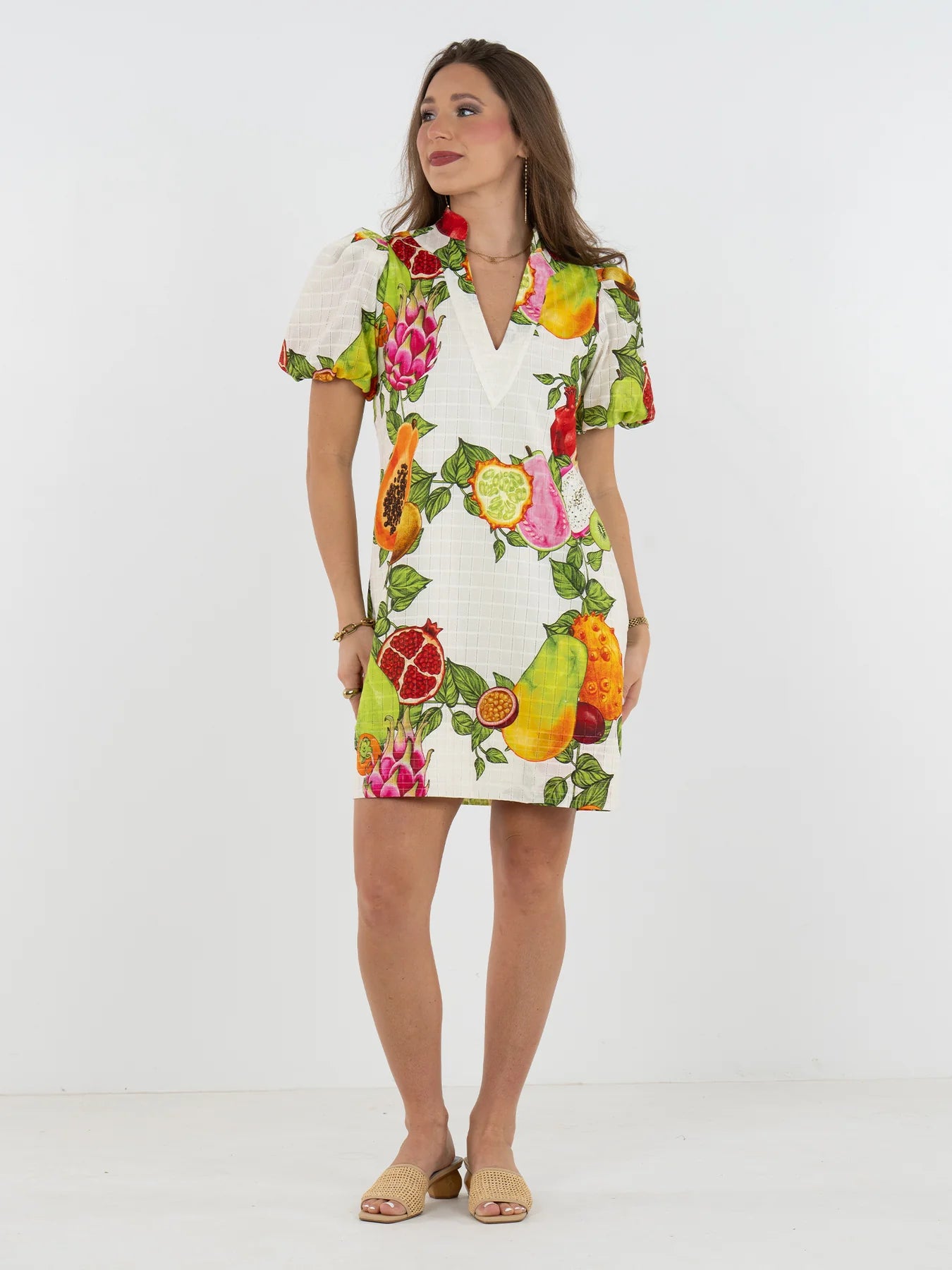 Woman wearing a colorful fruit print dress on a white background