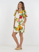 Woman wearing a colorful fruit-print dress on a white background