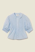 Light blue shirt with ruffled collar on a beige background