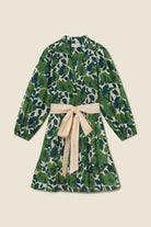 Green floral dress with a beige bow on a beige background
