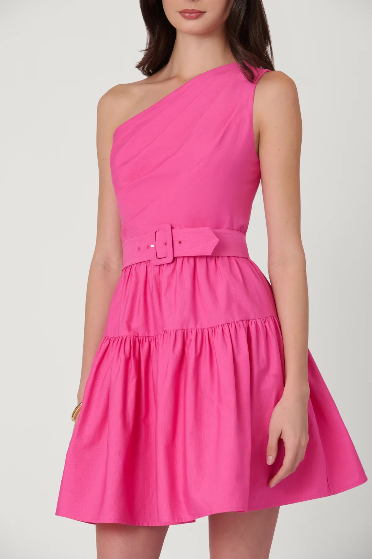 Pink one-shoulder dress with a belt on a white background