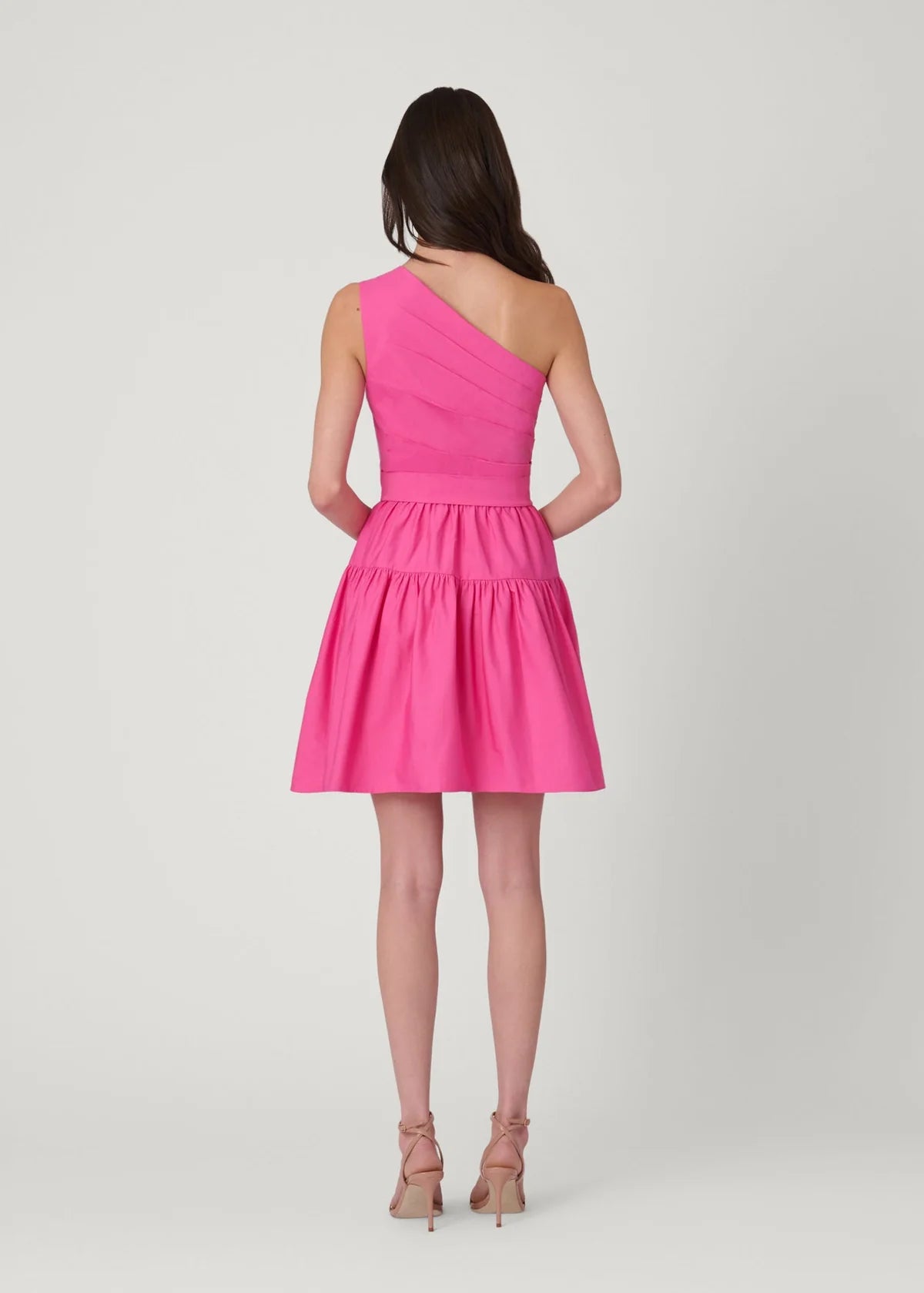 Woman wearing a pink one-shoulder dress on a white background