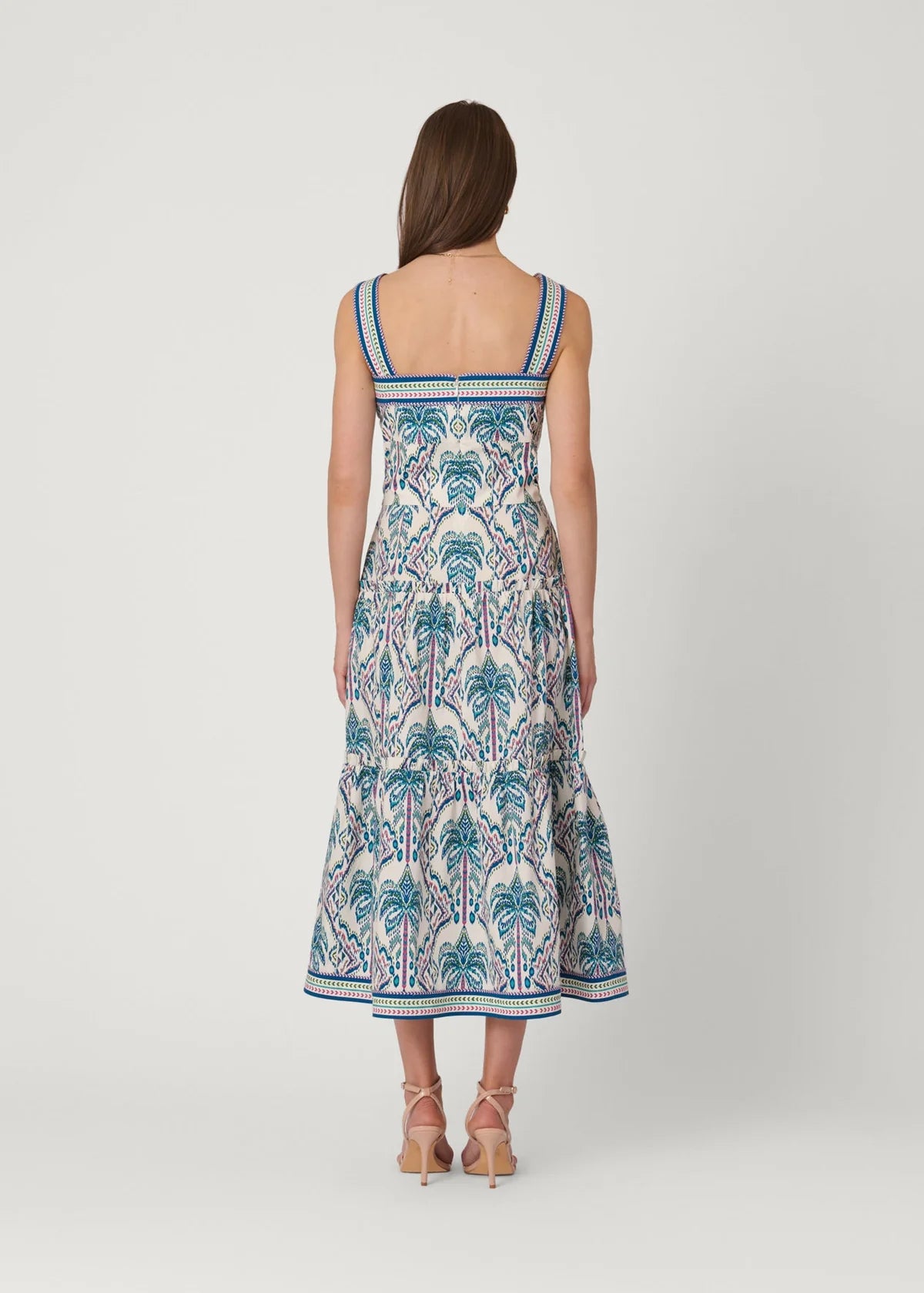 Woman wearing a palm tree patterned dress on a white background