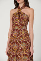 Woman wearing a patterned halter neck dress on a white background
