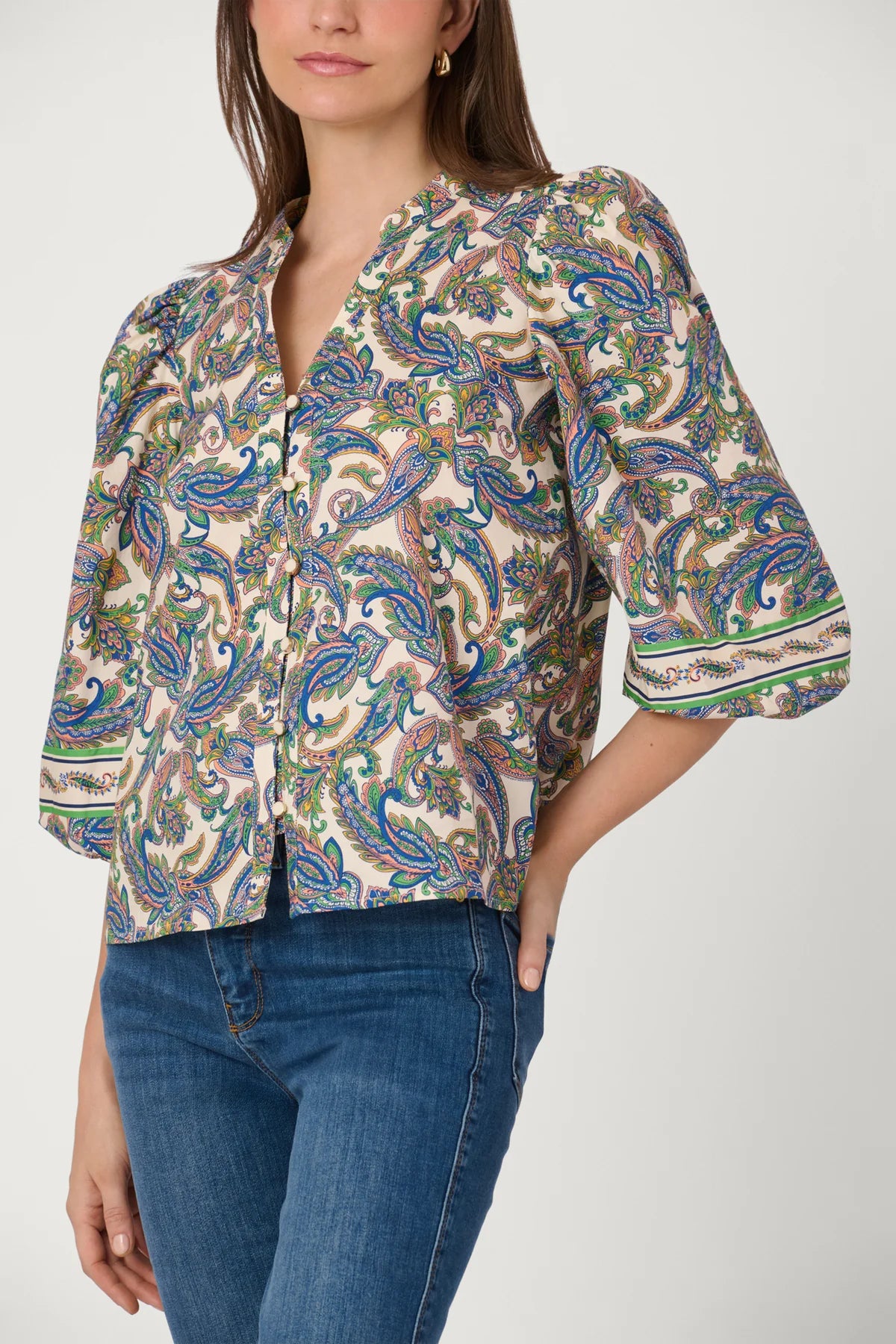 Woman wearing a patterned blouse and jeans on a white background