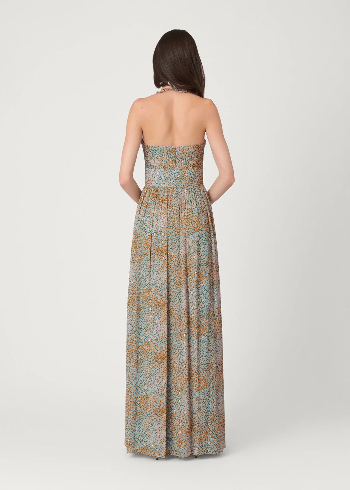 Woman wearing a strapless, long, patterned dress on a white background