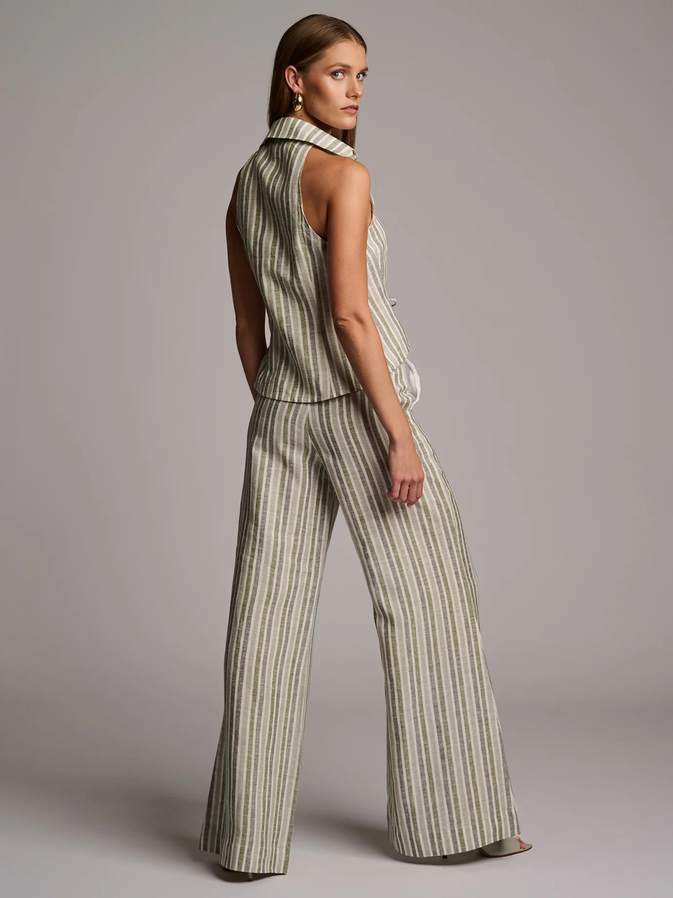 Woman wearing a striped sleeveless top and wide-leg pants against a plain background