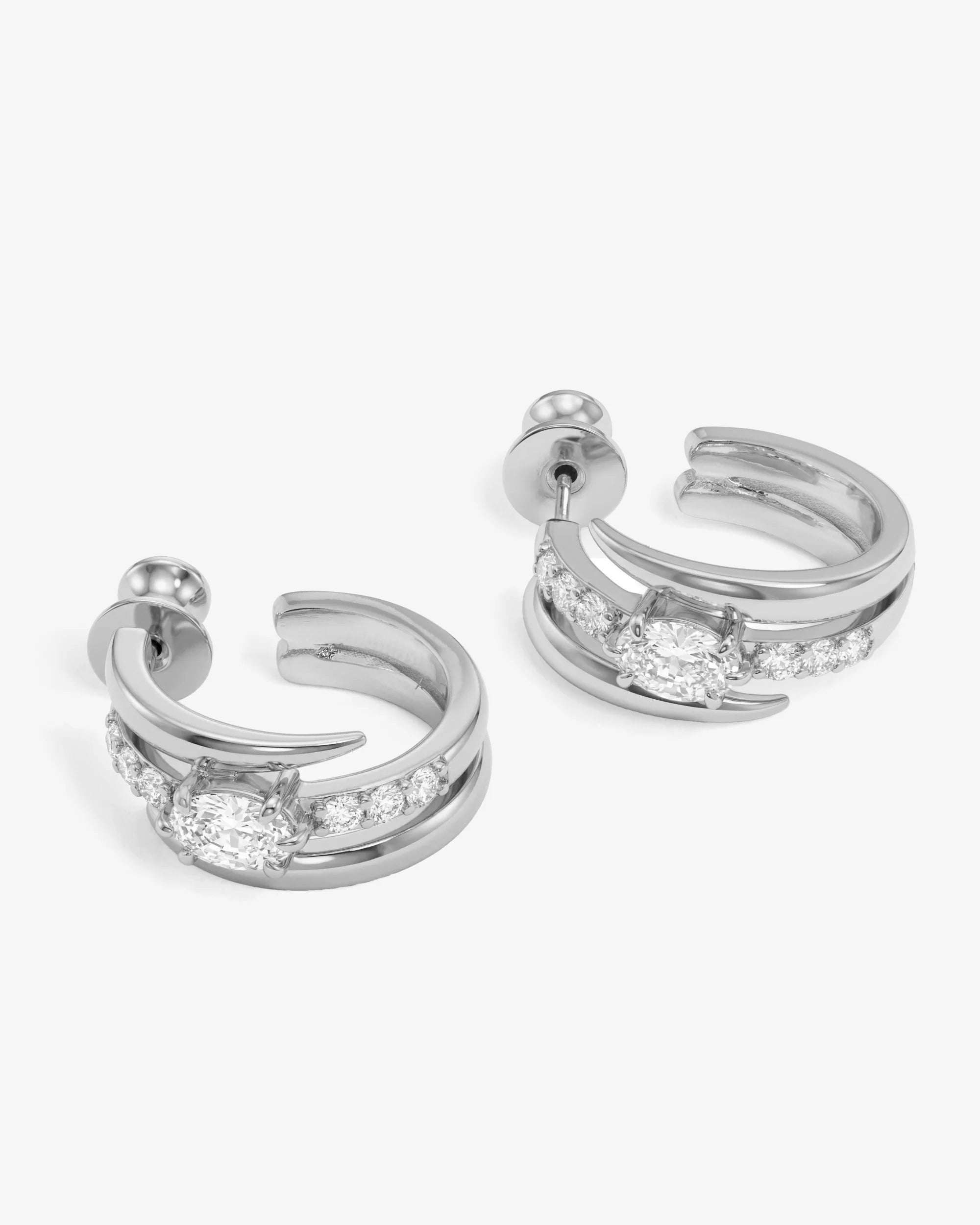 Pair of silver hoop earrings with clear gemstones on a white background
