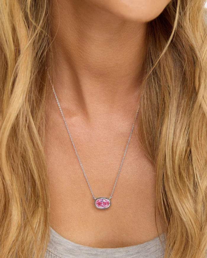 Necklace with a pink gemstone worn by a person with long blonde hair.
