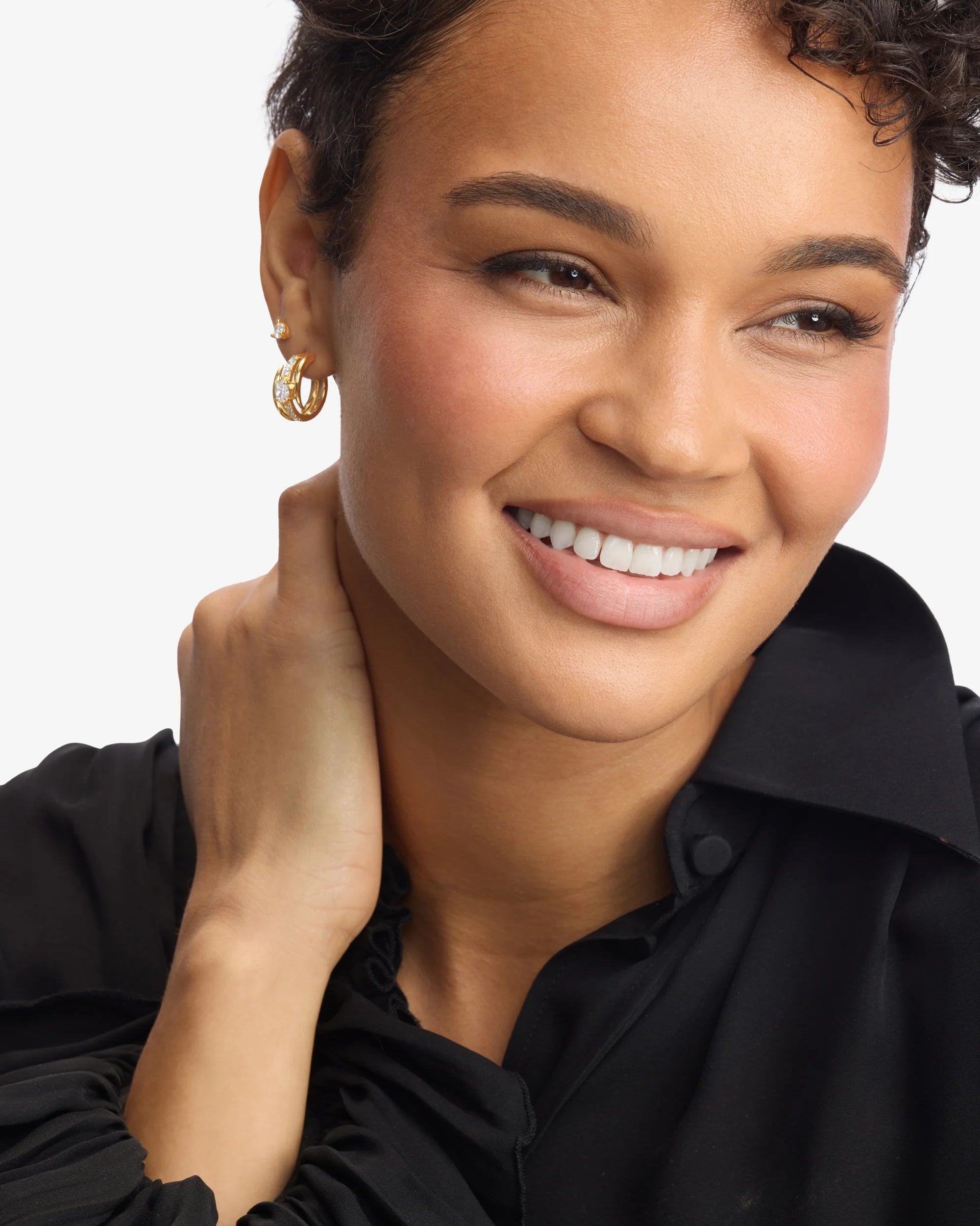 Woman wearing gold earrings with a plain background