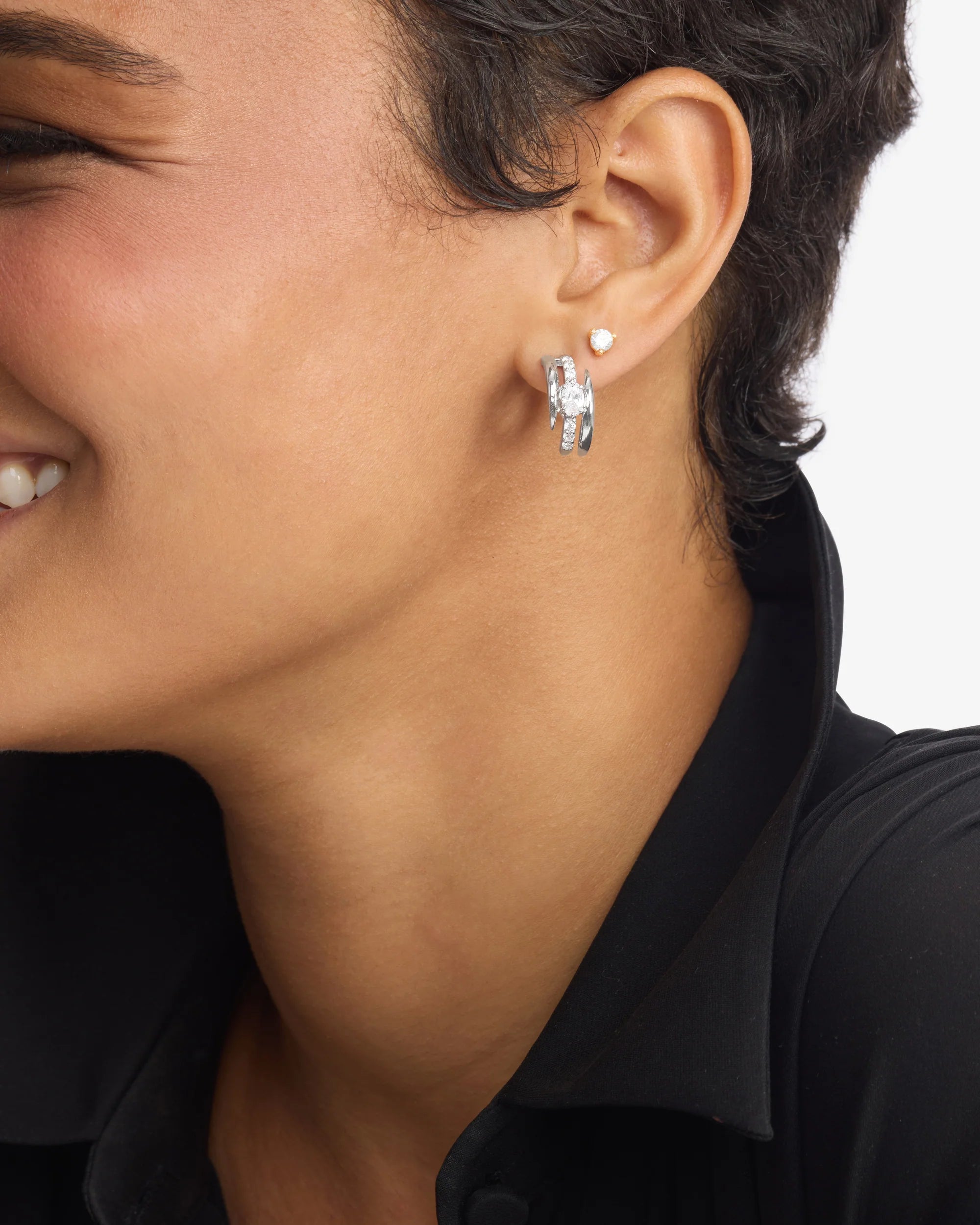 Close-up of a person wearing a silver earring on a plain background