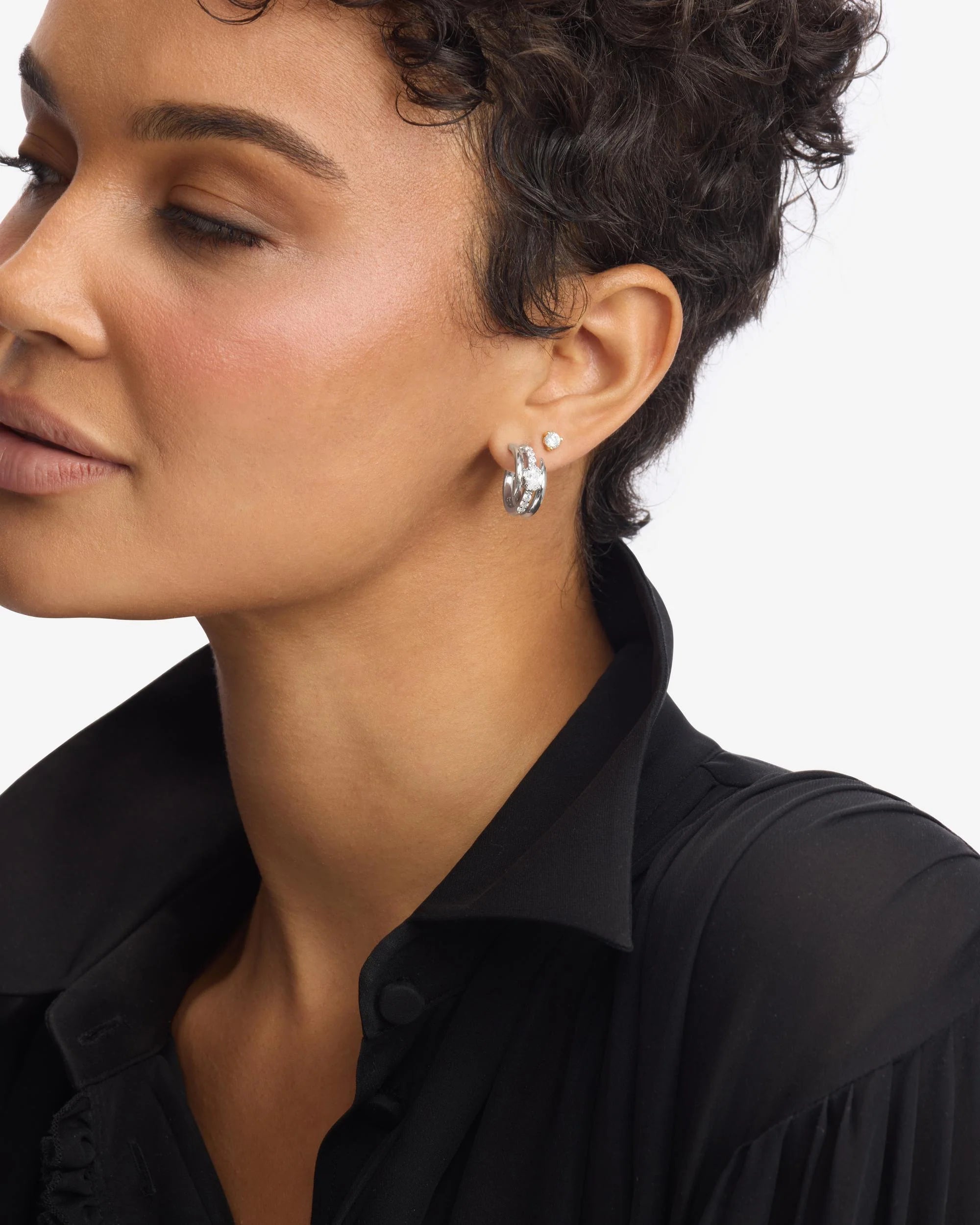 Close-up of a woman wearing silver earrings with a black shirt on a white background