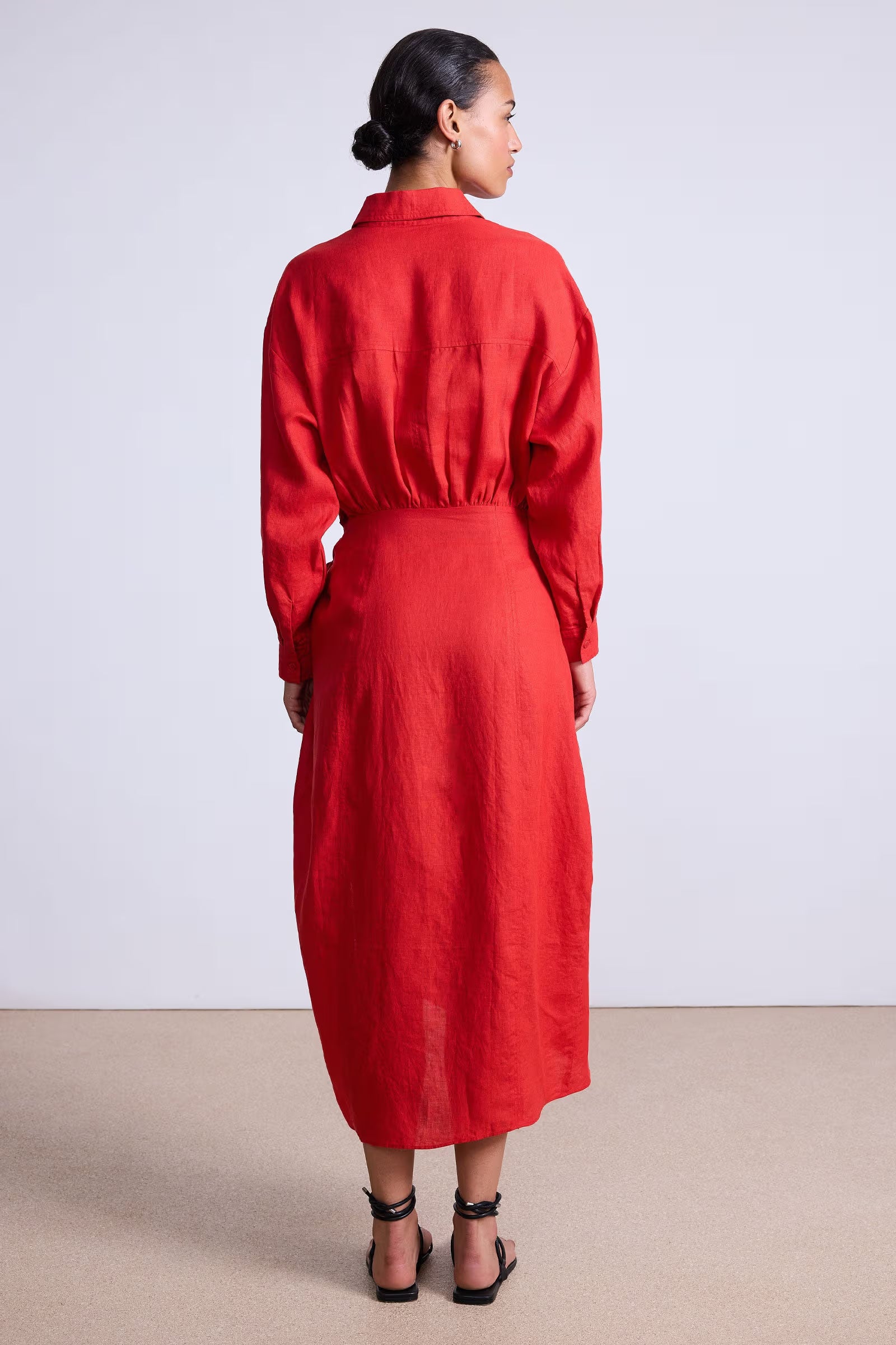 Woman wearing a red dress standing against a plain background