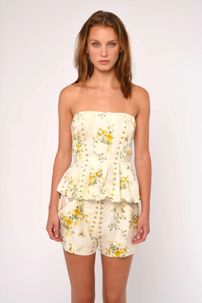 Woman wearing a floral strapless top and shorts on a white background