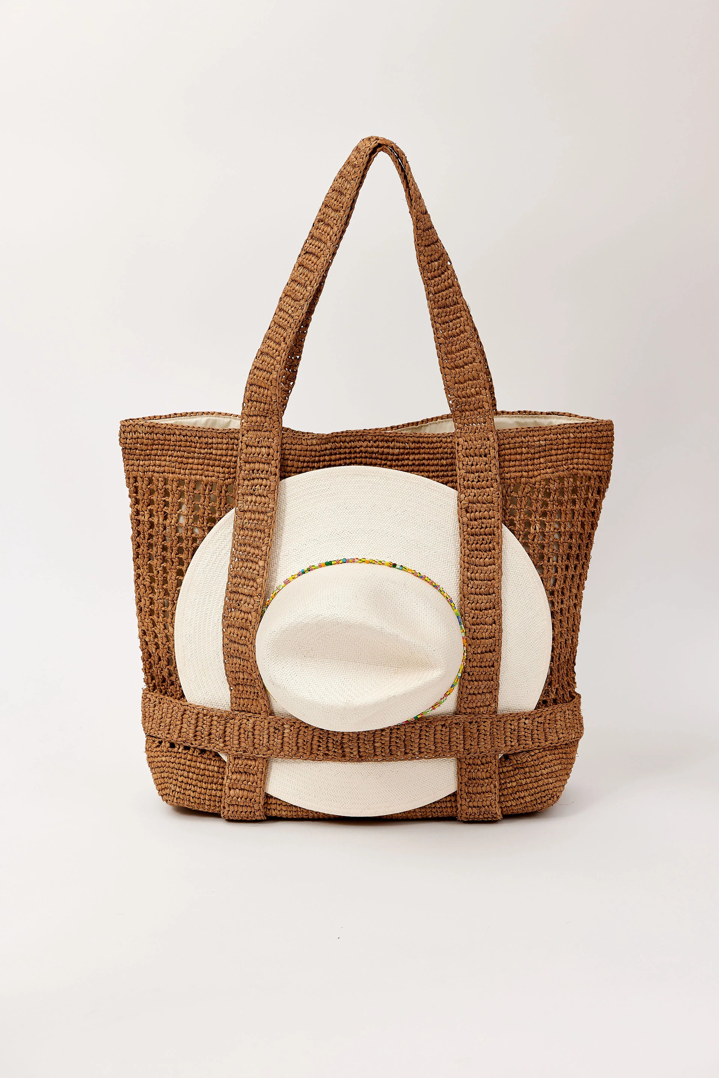 Woven brown tote bag with a white cushion inside on a light gray background