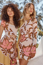 Two women wearing floral patterned dresses standing outdoors.