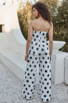 Woman wearing a strapless polka dot jumpsuit standing outdoors.