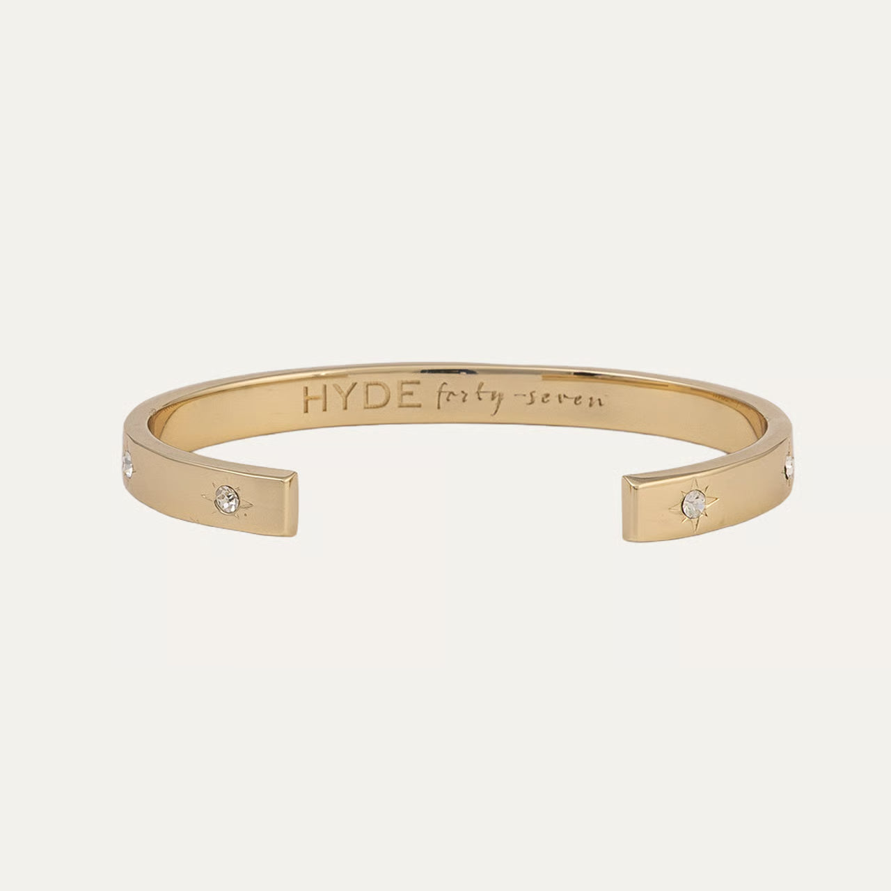 Gold bracelet with 'HYDE' engraving on a light beige background