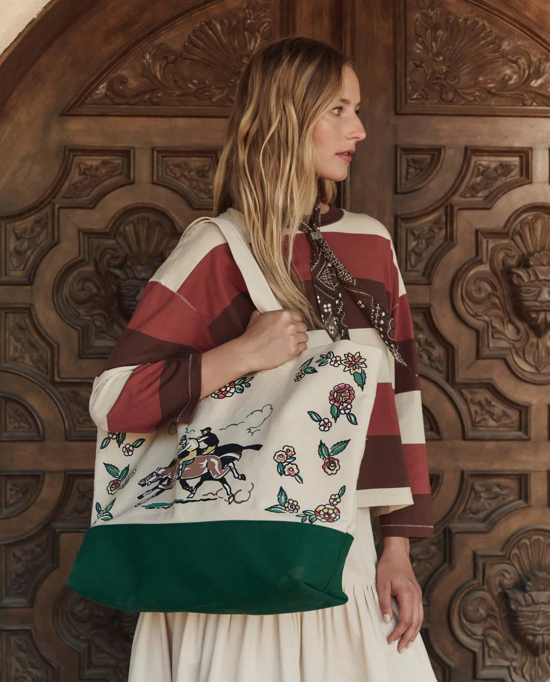 Woman holding a embroidered tote bag in front of a wooden door