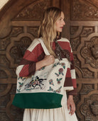 Woman holding a embroidered tote bag in front of a wooden door