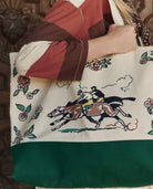 Tote bag with horse and floral design held by a person wearing a patchwork jacket.