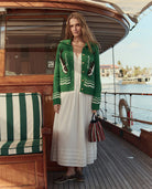 Woman in a green cardigan with feather patterns on a boat deck.
