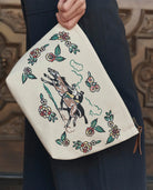 Clutch bag with donkey and floral design held by a person wearing a dark coat.