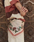 Person wearing a colorful outfit with floral embroidery against a decorative wooden background